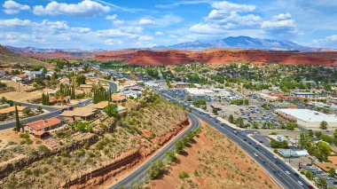 St. George Utah 'ın havadan görünüşü banliyö mahallelerinin hareketli olduğunu gösteriyor. Ticari bölge ve ikonik kırmızı kumtaşı uçurumları manzaralı Amerika' nın güneybatısında canlı bir gökyüzüne karşı kurulmuş.