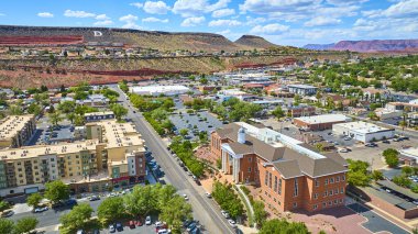 St. George Utah şehir merkezinin havadan görünüşü. Büyük 5. Bölge Adliyesi modern apartmanlar ve ikonik kızıl kaya kayalıkları tarafından çerçevelenmiş ağaçlarla kaplı caddeler berrak güneşli gökyüzü altında.