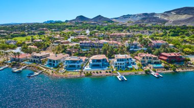 Las Vegas Gölü yakınlarındaki yemyeşil bir göl topluluğunda özel rıhtım ve havuzları olan lüks deniz manzaralı evler açık güneşli bir gökyüzünün altında çöl dağlarıyla çevrili.