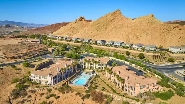Modern evlerin yakınındaki havuz ve palmiye ağaçları ve Las Vegas Gölü 'ndeki dramatik dağlarla dolu, güneşli gökyüzü altında lüks bir Akdeniz tarzı konut kompleksi.
