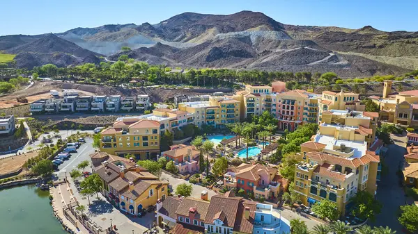 Las Vegas Gölü 'ndeki Akdeniz tarzı bir tatil köyünün havadan görünüşü. Renkli villalar, mavi havuzlar ve dramatik çöl tepeleri ve açık yaz gökyüzü üzerine kurulu sakin bir göl.