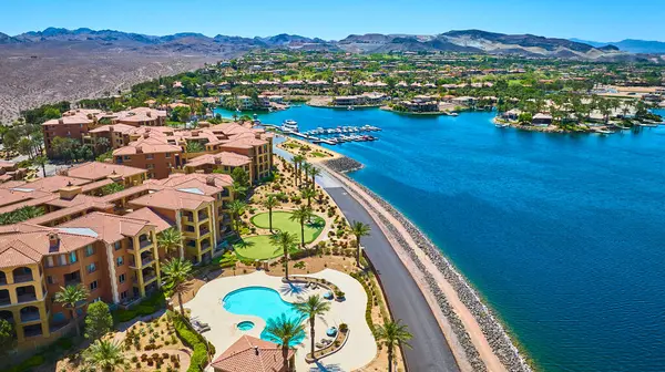 Las Vegas Gölü kıyısındaki lüks bir tatil köyünün havadan görünüşünde Akdeniz tarzı evler terakotta çatıları turkuaz bir havuz ve çöl dağlarıyla çevrili canlı bir marina var.