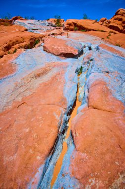 Gunlock State Park Utah 'ta açık bir gökyüzü altında mavi ve lavanta mineralleriyle çizgili canlı kumtaşı katmanları Amerikan Güneybatı Çölü' nün saf güzelliğini ve dayanıklılığını yakalıyor..
