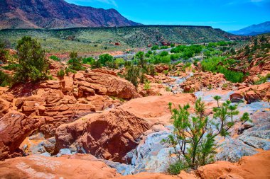 Canlı kırmızı kaya oluşumları ve yemyeşil bitki örtüsü Gunlock State Park Utah 'ta çarpıcı bir kontrastlık yaratır. Amerikan Güneybatı Çölü' nün doğal güzelliğini ve engebeli sükunetini yakalar.