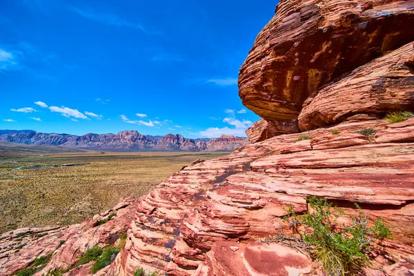 Calico Hills 'in dramatik kırmızı kumtaşı Las Vegas yakınlarındaki Red Rock Kanyonu' ndaki çöl vadisinde yükseliyor. Uzak dağlar ve Amerika 'nın vahşi güzelliğini gözler önüne seren engin mavi gökyüzü.