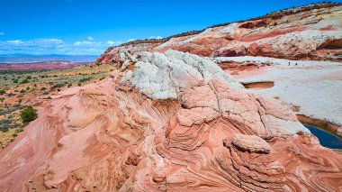Vermilion Cliffs Ulusal Anıtı Arizona 'daki Beyaz Cepte dönen kumtaşı manzarası canlı katmanlar, ölçek yürüyüşçüleri ve parlak mavi gökyüzü altında dramatik çöl manzarası.