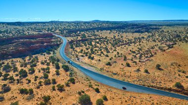 Mermer Kanyon Arizona yakınlarındaki Vermilion Kayalıkları 'nın engin çöl manzarasını geçen beyaz bir tır ve kırmızı bir araba ile dolambaçlı bir karayolu manzarası açık mavi gökyüzü macerası altında ve seyahat