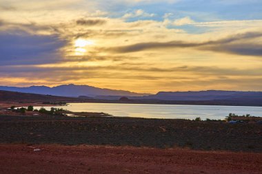 Günbatımı Sand Hollow Eyalet Parkı 'na altın ışık saçıyor. Sakin sular dramatik kayaları ve Utah Kasırgası' nda canlı bir gökyüzünü yansıtıyor. Açık hava için mükemmel bir çöl manzarası sunuyor.
