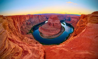 Günbatımında Arizona 'nın yakınlarında Horseshoe Bend' in nefes kesici panoramik manzarası Colorado Nehri 'nin etrafında dönen kırmızı kumtaşı kayalıkları ile altın saat gökyüzünün altında
