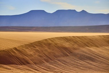 Altın ışık, Sand Hollow Eyalet Parkı 'ndaki kum tepeciğini aydınlatıyor. Utah, sakin bir gökyüzünün altındaki uzak dağlar Amerikan çölünün ıssız güzelliğini ve yalnızlığını yakalıyor..