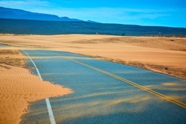 Altın kum tepeleriyle çevrili dolambaçlı çöl karayolu Sand Hollow Eyalet Parkı 'ndaki açık mavi gökyüzünün altında engebeli bir tepeye çıkar. Utah macerayı ve Amerika' nın güneybatısının ruhunu yakalar.