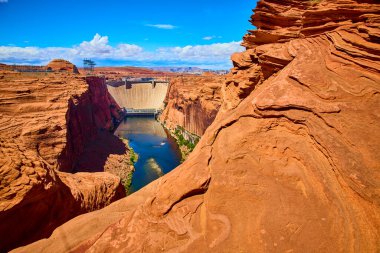 Glen Canyon Barajı, Arizona 'nın kuzeyindeki sarmal Colorado Nehri' nin üzerinde yükseliyor. Kırmızı kumtaşı kayalıkları ve parlak mavi gökyüzü, doğanın çarpıcı dengesini ve mühendisliği gözler önüne seriyor..