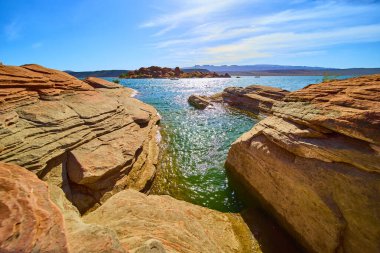 Canlı kırmızı kumtaşı oluşumları, Utah Kasırgası 'ndaki Sand Hollow Eyalet Parkı' ndaki parlak mavi suları çerçeveler. Amerikan Güneybatı Çölü 'nün ortasındaki maceraya ve sükunete davetiye çıkarıyor.