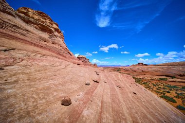 Arizona Sayfası yakınlarındaki Arı Kovanı Patikası boyunca parlak mavi gökyüzü altında parlak kırmızı kumtaşı dalgaları yükseliyor. Çarpıcı kaya oluşumları ve seyrek çöl bitkileri Amerikan ruhunu yansıtıyor.