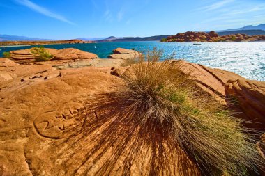 Güneş ışığı altındaki kırmızı kumtaşına işlenmiş kalp şeklindeki oymalar Utah Kasırgası 'nda parlayan Sand Hollow rezervuarı ve çöl fırçaları Amerika' nın güneybatısındaki macera doğasını ve insan ilişkilerini yakalıyor.