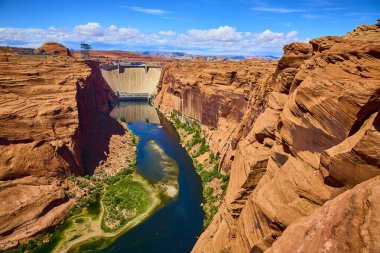 Glen Canyon Barajı 'nın havadan görünüşü derin mavi Colorado Nehri' ni çevreleyen Arizona Sayfası yakınlarındaki canlı kırmızı kayalıklar arasında. Amerika 'nın güneybatısındaki şaşırtıcı mühendislik harikası ve doğal güzellik karşıtlığı.