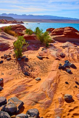 Canlı turuncu kumtaşı ve çöl çalıları Utah Kasırgası yakınlarındaki Sand Hollow Gölü 'nün mavi sularına, berrak gökyüzünün altındaki uzak dağlara, Amerika' nın güneybatısının engebeli güzelliğini gösteriyor.
