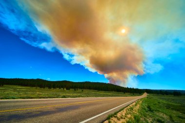 Orman yangınından çıkan muazzam dumanlar Bryce Canyon Ulusal Parkı 'nın yakınındaki bir çam ormanının üzerinde yükseliyor. Güneşin puslu bir günde parladığı Utah Kanyonu' nun açık hava ateşini vurguluyor..