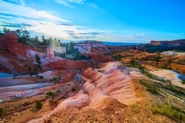 Gün doğumu ışığı, Bryce Canyon Ulusal Parkı Utah 'taki Queens Garden ve Navajo Döngüsü' nün vudu kaya oluşumlarını ve canlı arazisini aydınlatarak çarpıcı ve maceracı bir manzara yaratır..