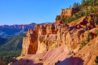 Sıcak güneş ışığı Utah 'taki Bryce Canyon Ulusal Parkı' nın ikonik hudu kayalıklarını ve kırmızı kaya oluşumlarını aydınlatıyor. Çam ağaçları yemyeşil ve Amerika Birleşik Devletleri 'nin ruhunu yansıtan manzaralı bir manzara.