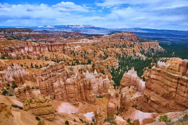 Utah 'taki Bryce Canyon Ulusal Parkı' ndaki çam ormanının üzerinde canlı turuncu kabadayılar kulesi. Uzak mesafelere ve dramatik gökyüzüne bakarak ABD 'deki Sunrise Point' ten ilham verici bir manzara yaratıyor..