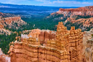 Yoğun bir çam ormanının üzerinde, Bryce Canyon Ulusal Parkı 'ndaki Sunrise Point' te geniş görüş açısı ve gökyüzü ile çarpıcı hudu kaya oluşumları yükseliyor..