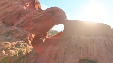 Nevada 'daki Gold Butte Ulusal Anıtı' nda bulunan kırmızı kaya oluşumları ve doğal kemer boyunca uçan havadan uçarak güneşli çöl manzarasını ve macera hissi veren Whitney Pocket arazisini gözler önüne serdi.