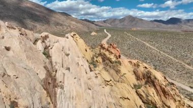 Nevada Bunkerville yakınlarındaki Gold Butte Ulusal Anıtı 'ndaki dramatik kumtaşı uçurumları ve dolambaçlı toprak yolda uçarak engin çöl manzarasını ve parlak mavi bir Whitney Pocket' i yakalıyor.