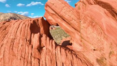 Nevada 'daki Gold Butte Ulusal Anıtı' ndaki dramatik kırmızı kaya kemerinin üzerinden geçen hava, maceralı bir yolculuk için parlak mavi gökyüzünün altındaki çöl ve dağların geniş bir manzarasına geçiş yapar.