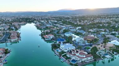 Hava İzleme Çekimi: Las Vegas 'ta sakin bir gölün üzerinde gündoğumu manzaralı lüks yaşam deneyimi. Bu dingin yerleşim alanındaki canlı evlere, yemyeşil bahçelere ve görkemli dağlara hayran kaldım.