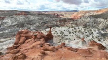 Dinamik hava yayı ikonik Toadstool Hoodoo Patikası 'nı görüntüler. Heykeltraş edilmiş kırmızı kaya oluşumları, katmanlı çöl arazileri ve dramatik bir gökyüzü altında geniş Grand Escalante manzaraları..