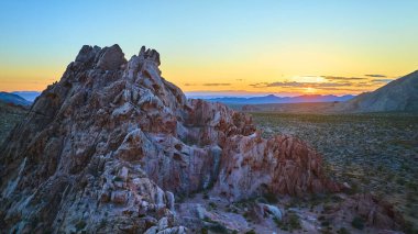 Güneşin batışı, altın saat boyunca engin çöl arazisinin ötesinde batan Nevada 'daki Whitney Pocket Ulusal Anıtı' nda engebeli kumtaşlarını aydınlatıyor.