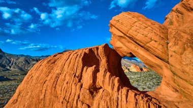 Çarpıcı kırmızı kumtaşı oluşumu Whitney Pocket 'in çöl zemininden yükseliyor. Nevada Ulusal Anıtı. Canlı mavi gökyüzü ve engebeli arazi dramatik bir sahne yaratıyor.
