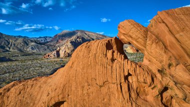 Whitney Pocket 'da kumtaşı kemeri oluşumunun canlı hava görüntüsü. Nevada Ulusal Anıtı. Geniş bir çöl ve dağ manzarası açık mavi gökyüzünün altında.