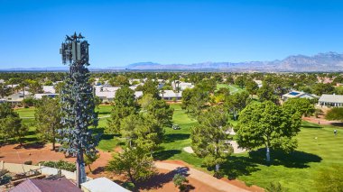 Ağaç kılığında baz istasyonu Las Vegas 'ta açık mavi gökyüzünün altında yeşil bir golf sahasının ve banliyö evlerinin üzerinde duruyor.