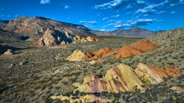 Whitney Pocket in Gold Butte Ulusal Anıtı Nevada 'daki güneşli hava manzarasında renkli kumtaşı oluşumları engebeli dağlar ve dağınık Joshua ağaçları derin mavi bir gökyüzü altında