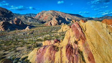 Nevada 'daki Altın Butte Ulusal Anıtı' nın canlı hava görüntüsü Whitney Pockets eşsiz kumtaşı oluşumları Joshua ağaçları ve açık mavi gökyüzü altındaki dağ arazisi