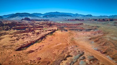 Uçsuz bucaksız kızıl kaya oluşumları çöl düzlükleri ve açık mavi gökyüzünün altındaki uzak dağlar Altın Göt Ulusal Anıtı 'nın engebeli güzelliğini yakalıyor.