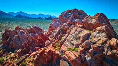 Altın Göt Ulusal Anıtı Nevada 'daki Whitney Pocket ovasının üzerinde açık çöl üzerinde canlı mavi gökyüzünün altında koyu kırmızı kaya oluşumları yükseliyor.