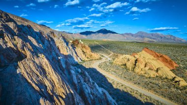 Whitney Pocket kaya oluşumları engebeli toprak yollar ve Nevada 'nın Gold Butte Ulusal Anıtı' ndaki uzak dağlar parlak mavi gökyüzünün altında canlı bir hava görüntüsüyle ele geçirildi.