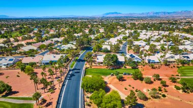 Las Vegas 'ın banliyölerinde geniş bir hava manzarası var. Golf sahası, çim yolları, sokaklar ve dağ arkaplanı var.