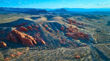 Nevada Gold Butte Ulusal Anıtı 'nda Whitney Pocket' in hava görüntüsü dramatik kırmızı kaya oluşumları geniş çöl arazileri ve uzak sıradağlar içeriyor.