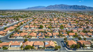 Terracotta çatıları geniş sokakları ve berrak gökyüzünün altındaki uzak dağları olan banliyö evlerinin geniş manzarası.
