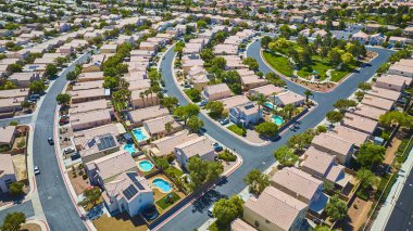 Cilalı banliyö sokakları güneşli bir Central Park 'ı çevreleyen bronz çatı evleri ve parlak gün ortası ışığı altında ışıl ışıl arka bahçe havuzlarıyla çevrili.