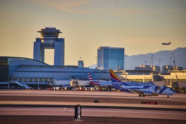 Las Vegas havaalanının pistinde ticari bir uçak taksisi şehrin silueti ve arka planında Nevada dağları açık mavi gökyüzünün altında