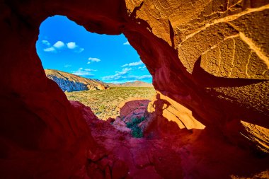 Canlı kırmızı kaya kemeri oluşumu Nevada çöl manzarasını çerçeveliyor. Whitney Pocket yakınlarındaki Gold Butte Ulusal Anıtı 'ndaki mağara duvarına bir insan gölgesi uzanıyor.