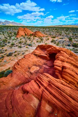 Çarpıcı kırmızı kumtaşı kayaları Nevada 'daki Gold Butte Ulusal Anıtı' nın çöl manzarasına hakim. Whitney Pocket manzarası ve bulutlarla dolu bir gökyüzü.
