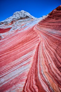 Vermilion Cliffs Ulusal Anıtı Arizona 'da, üzerinde parlak mavi gökyüzü bulunan, bu çöl manzarasının eşsiz dokularını ve renklerini vurgulayan canlı kumtaşı dalgaları kıvrılıyor.