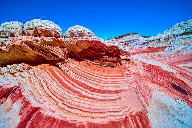 Kırmızı ve beyaz kumtaşı şeritleri Vermilion Cliffs Ulusal Anıtı Arizona 'da beyaz cepte çarpıcı kaya kubbeleri ve göz kamaştırıcı bir çöl manzarası yaratan parlak mavi gökyüzü ile dalgalanır.