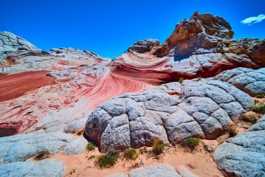 Gerçeküstü beyaz kaya tepecikleri ve dönen kırmızı kumtaşı Vermilion Cliffs Arizona 'daki White Pocket' da canlı mavi gökyüzü altında macera ve doğa temaları için mükemmel bir uzaylı manzarası yaratır.